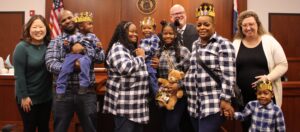 A family in blue plaid shirts celebrating the adoption of a young boy in a courtroom