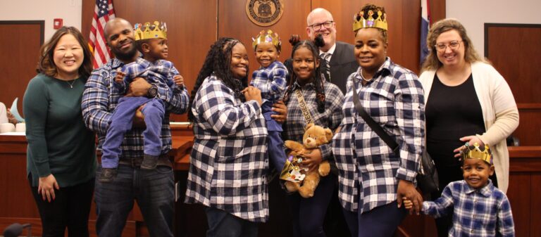 A family in blue plaid shirts celebrating the adoption of a young boy in a courtroom